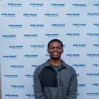 Boy with hands crossed in front of GV Alumni backdrop